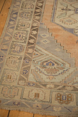 Distressed vintage Oushak rug showing soft apricot, sand, and pale blue patterned detail.