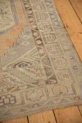 Distressed vintage Oushak runner corner with muted geometric border and short fringe.