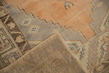 Distressed Oushak rug corner, revealing apricot, silver pile and its hand-knotted foundation.