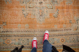 Distressed Oushak carpet detail, showing worn orange, celadon green, and ivory patterns.