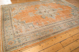 Close-up of distressed Oushak pile with orange, celadon border and secured edge.