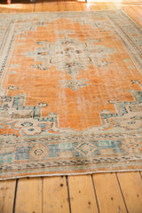 Distressed Oushak rug corner with secured fringe and worn orange, celadon green border.