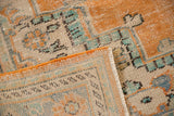 Vintage Oushak rug close-up: worn ivory and orange pile, faint foundation, and secured edge.