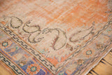Distressed vintage Oushak carpet corner; bold orange field, ivory paisley boteh, blue border.