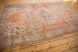 Distressed orange field, ivory border with faded paisley botehs on a vintage Oushak rug.