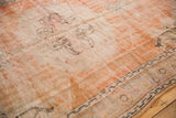 Distressed texture of a vintage Oushak rug with faded orange, ivory, and charcoal boteh motifs.