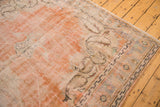 Textural detail of distressed vintage Oushak rug with soft orange, cream, and faded patterns.