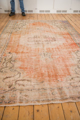 Fringed edge and distressed orange ivory pile texture of a vintage Oushak carpet.