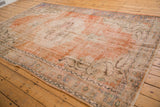 Distressed texture of vintage Oushak rug showing faded orange and ivory, with subtle boteh details.