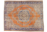 Hand-knotted distressed Oushak rug, burnt orange field, royal blue medallion, ivory florals.