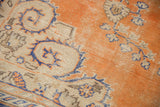 Distressed Oushak rug detail: burnt orange, ivory, royal blue floral motifs, visible foundation.
