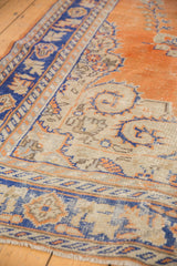 Distressed Oushak rug texture, featuring burnt orange, blue infinity ribbon, and ivory florals.