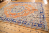 Distressed Oushak rug corner with royal blue border, antique ivory motifs, and worn orange field.
