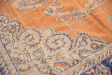 Distressed burnt orange field with scrolling floral bouquets and blue-outlined ivory border.