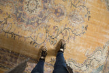 Distressed vintage Oushak carpet highlighting worn pile, etched foundation, faded gold and blue patterns.