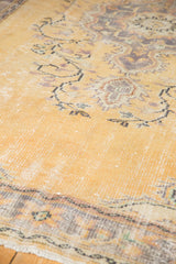 Distressed pale dusty gold Oushak carpet pile with etched foundation and faded floral vines.