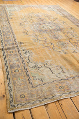 Distressed Oushak rug corner, showing etched foundation, pale gold pile, and subtle green motifs.