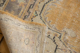 Vintage distressed Oushak rug showing faded gold pile, hand knotted foundation, secured edge.