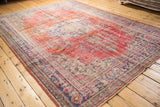 Vintage distressed Oushak rug corner, with faded cherry red patterns and visible foundation wear.