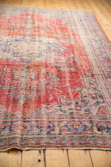 Distressed Oushak rug with visible fringe, cherry red, navy, and ivory border.