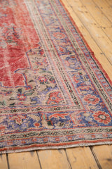 Visible foundation and dusty navy floral border on distressed vintage Oushak rug.