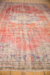 Distressed cherry red and dusty navy border with worn fringe on a vintage Oushak rug.