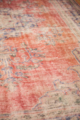 Decorative distressed pile of a vintage Oushak rug, showing exposed foundation and muted florals.