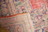 Vintage Distressed Oushak rug corner showing worn pile texture, colorful motifs, and fringe.