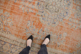 Distressed vintage Oushak carpet with faded burnt orange, navy, and exposed foundation.