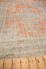 Faded orange, ivory, and blue distressed Oushak carpet end with secure fringe.