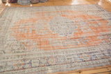 Distressed texture of faded orange and ivory pile, revealing knot heads and navy blue border motifs.