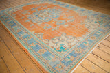 Hand knotted distressed Oushak rug corner displaying tangerine field and sky blue floral border.