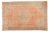 Distressed vintage Oushak carpet with pale blue roundel medallion on a muted peach field.