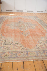 Vintage distressed Oushak carpet, textural dusty peach field with pale blue trefoil motifs.