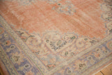 Distressed Oushak rug corner detail, soft peach field, pale blue, ivory scalloped border.