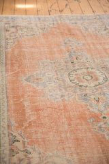 Textured dusty peach Oushak rug pile with faded pale royal blue motifs.