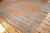 Vintage distressed Oushak rug corner showing faded peach field and pale blue border.