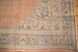 Distressed Oushak rug corner, showing even wear, pale blue, dusty peach borders, and fringe.