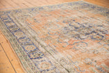 Vintage distressed Oushak carpet with worn apricot field, faded navy border, and visible etching.