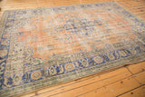 Distressed texture, apricot and navy floral vinery on vintage Oushak rug corner.