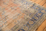 Distressed vintage Oushak rug corner with abrashes, navy border, and apricot floral vinery.