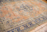 Distressed vintage Oushak carpet corner with apricot field, navy border, and faded floral vinery.
