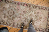 Distressed vintage Oushak runner with triple medallion, etched pale mauve, ivory, and silver textures.