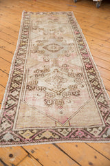 Distressed vintage Oushak rug close-up, faded pale mauve, brown geometric medallion and border.