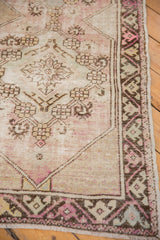 Distressed Oushak runner corner showcasing geometric motifs and worn pile texture in blush and brown.