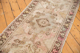 Distressed vintage Oushak runner showing triple medallion, etched pile, pale mauve and blush.