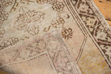 Distressed Oushak pile in pale mauve and ivory, revealing its hand-knotted foundation.