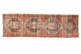 Distressed vintage Oushak runner, pale brick red and charcoal geometric gul motifs. 3'5