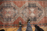 Distressed Oushak runner with faded brick red, charcoal, and beige geometric pattern.