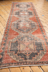 Distressed vintage Oushak rug with geometric motifs in pale brick red, charcoal, and beige.